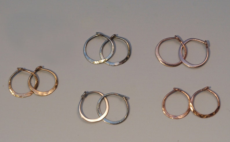 May include: Set of six hammered hoop earrings in silver, gold, and rose gold. The earrings are all different sizes.