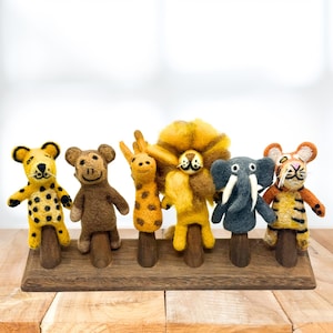 May include: A collection of handmade felt animal finger puppets, including a cheetah, monkey, giraffe, lion, elephant, and tiger. Each puppet is attached to a wooden base, perfect for imaginative play or storytelling. The puppets are brightly colored and detailed.