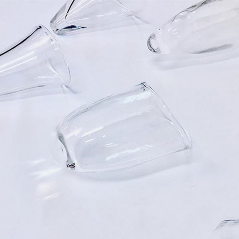 May include: A set of five clear glass cups with a rounded shape. The cups are arranged on a white surface.