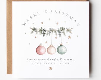 May include: A Christmas card with a brown envelope. The white card features the text "MERRY CHRISTMAS" above a garland with three hanging ornaments in pink, white, and green. The text "to a wonderful mum" and "LOVE RACHEL & JOE" are below.