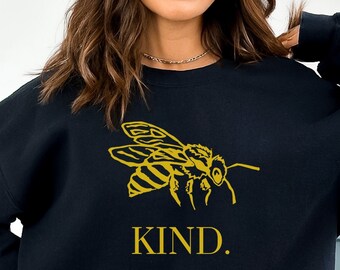 May include: Black sweatshirt with a gold bee graphic and the word "KIND." printed below it.