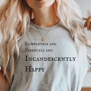 May include: A gray t-shirt with the text "Completely and Perfectly and Incandescently Happy" printed on the front.
