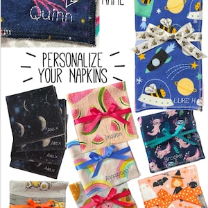 May include: A collection of personalized napkins with various designs, including space, watermelon, rainbows, and Halloween themes. Each napkin is tied with a ribbon and features a name. The text "PERSONALIZE YOUR NAPKINS" is also visible.