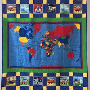 May include: A blue and yellow patchwork quilt with a world map in the center. The map is surrounded by a green border and the quilt is decorated with small squares featuring images of cars, airplanes, and other travel-related themes.
