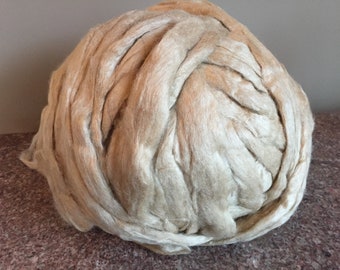 Pode incluir: Uma grande bola de fibra natural de cor bege, provavelmente algodão ou linho, para fiar ou tecer.