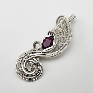 May include: A silver wire wrapped pendant featuring a purple gemstone. The pendant is shaped like a stylized leaf with a swirl at the bottom.