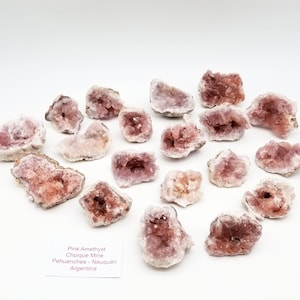 May include: A collection of pink amethyst crystal clusters from the Choique Mine in Pehuenches, Neuquén, Argentina. The crystals are a pale pink color and have a natural, rough texture.