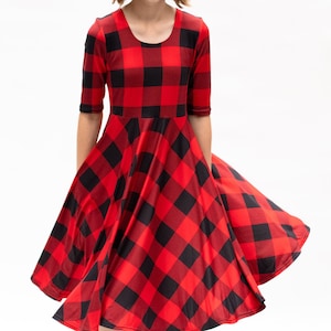 May include: A red and black plaid dress with a scoop neck and 3/4 sleeves. The dress has a flared skirt and is made of a soft, stretchy fabric.