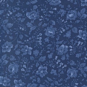 May include: A close-up of a fabric with a dark blue background and a repeating floral pattern in shades of blue. The design features various flowers, leaves, and vines, creating a classic, vintage aesthetic. The fabric has a textured appearance.