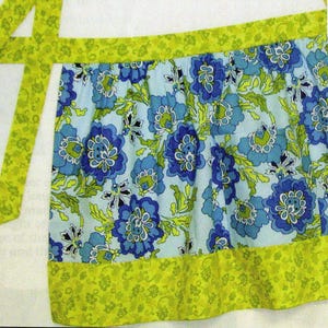 May include: A blue and green floral print apron with a lime green trim and matching tie.