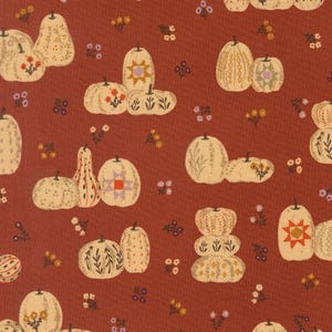 May include: A rust-colored fabric featuring a repeating pattern of cream-colored pumpkins and gourds. The pumpkins are decorated with various motifs including geometric star shapes, delicate floral sprigs, and vertical line patterns.