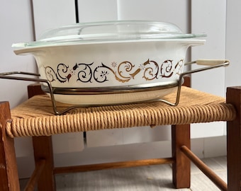 Vintage Pyrex Style 043 1.5 Quart Casserole bowl with lid. White and gold Empire scroll pattern with metal cradle. Read for condition