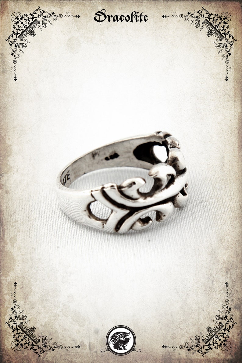 Puede incluir: Un anillo de plata con un dise&ntilde;o detallado y ornamentado. El anillo est&aacute; hecho de una sola pieza de metal y tiene un acabado liso y pulido.