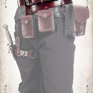 May include: A brown leather belt with silver accents and multiple pouches. The belt has a buckle with a decorative design and the word "Dracolite" is written on the belt.