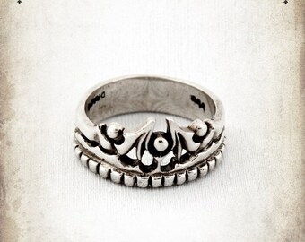 May include: A silver ring with a crown design. The ring is made of sterling silver and has a detailed design.