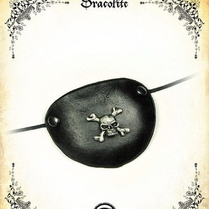 Könnte beinhalten: Ein schwarzes Leder-Piraten-Augenpflaster mit einem silbernen Totenkopf- und Knochenkreuz-Design.