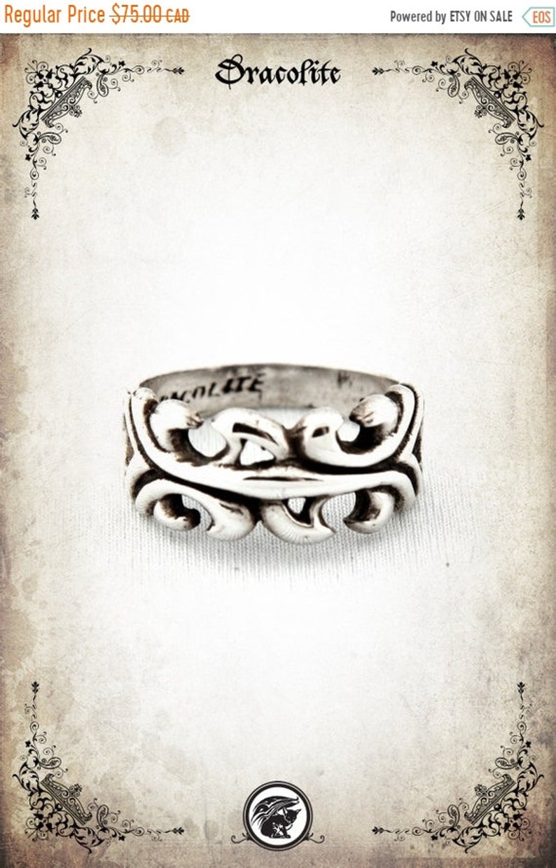 Puede incluir: Anillo de plata con un dise&ntilde;o decorativo y ornamentado. El anillo est&aacute; grabado con la palabra "Dracolite".