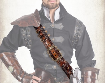 Könnte beinhalten: Ein braunes Leder-Schulterband mit einer Metallschnalle und einem dekorativen Design. Das Band hat eine Reihe kleiner Taschen zum Verstauen von Munition. Das Band wird von einer Person in einem dunklen Hemd und Lederhosen getragen.