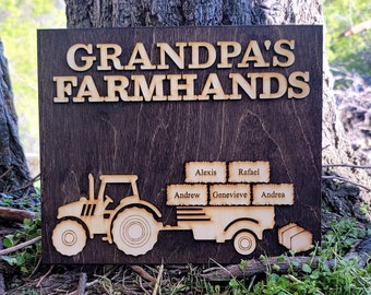 May include: A wooden sign with the text "Grandpa's Farmhands" and a cutout image of a tractor pulling a trailer. The trailer is loaded with wooden blocks with the names Alexis, Rafael, Andrew, Genevieve, and Andrea.