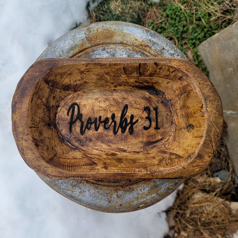 May include: A wooden dough bowl with a dark brown stain. The bowl has the words "Proverbs 31" inscribed on the inside.