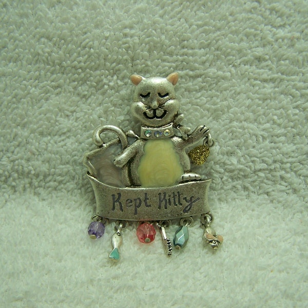 Pewter cat declares on a banner that she is a well 'Kept Kitty' . Charms are hanging from the banner. Vintage TC brooch.