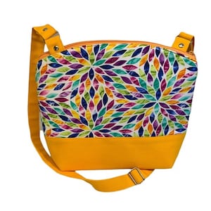 May include: A yellow crossbody bag with a colorful floral pattern. The bag has a zipper closure and a long adjustable strap.