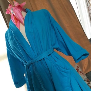 May include: A bright blue robe with a tie belt. The robe has long sleeves and a relaxed fit.