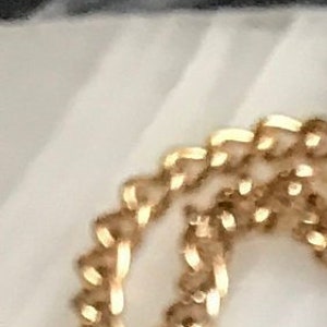 May include: A gold chain necklace with an oval pendant featuring a black background and a colorful floral design. The pendant has a gold rim and the flowers are pink, white, blue, and green.