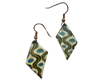May include: A pair of diamond-shaped earrings with a black, white, and blue geometric pattern. The earrings have a copper wire hook.