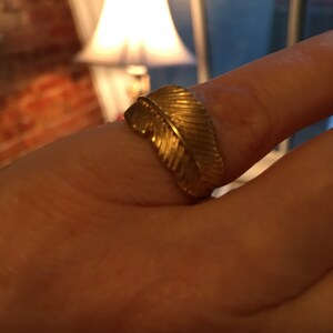 May include: A gold ring with a feather design.