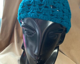 May include: A teal blue crocheted hat with a delicate openwork design.
