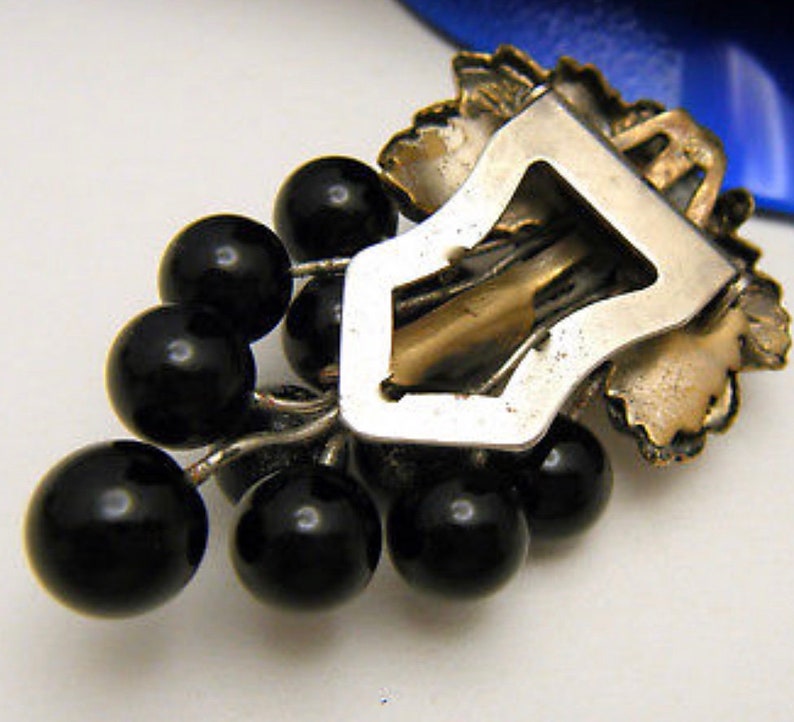 back side of art deco dress clip showing brass fold over clip