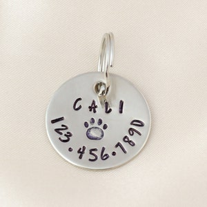 Silver Dog tag hand stamped with pet name, symbol and Phone number.