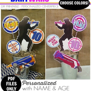 May include: Printable party decorations for a dart wars themed birthday party. The decorations include a silhouette of a person holding a dart gun, a target with the words "Happy Birthday" and a name, and a circle with the number 10. The colors are pink, purple, blue, orange, and white.