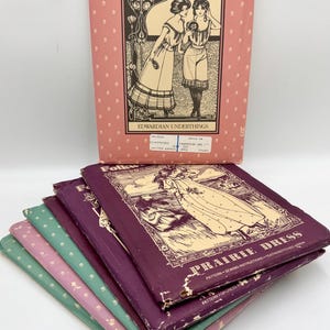 May include: A stack of vintage sewing patterns for Edwardian underthings and a prairie dress. The patterns are in various colors, including purple, green, and pink. The patterns feature illustrations of women wearing the garments.