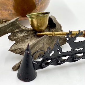 May include: A vintage copper pot with a brass lid and a decorative metal stand. The stand features a deer silhouette and a twisted metal design.