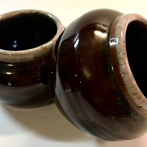May include: Two brown ceramic bowls with a white rim. The bowls are glazed and have a shiny finish.