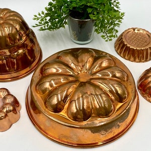 May include: Set of five copper cake molds with different floral designs. The molds are shiny and have a vintage look.