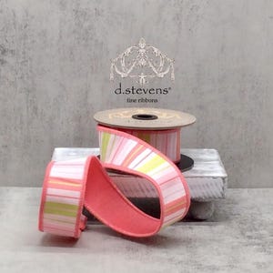 May include: A spool of pink, white and yellow striped ribbon with a coral coloured backing. The ribbon is on a spool with a label that reads "d.stevens fine ribbons".