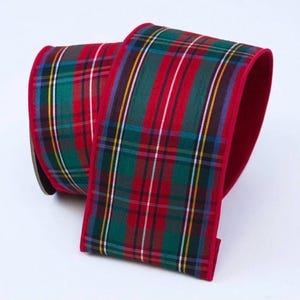 Pode incluir: Um rolo largo de fita de tecido com um padrão clássico de xadrez tartan em tons de verde floresta, vermelho profundo e azul marinho, acentuado com finas riscas brancas e amarelas. As bordas da fita têm um acabamento em vermelho sólido.