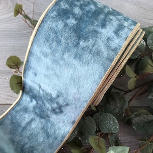 Könnte beinhalten: Nahaufnahme einer Rolle blauem Samtband mit goldener Bordüre. Das Band ist dick und weich, mit einer weichen Textur. Die goldene Bordüre sorgt für einen Hauch von Eleganz. Dekoratives Band für Bastelarbeiten und Geschenkverpackungen.
