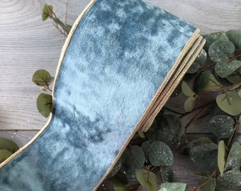 May include: Close-up of a roll of blue velvet ribbon with a gold trim. The ribbon is thick and plush, with a soft texture. The gold trim adds a touch of elegance. Decorative ribbon for crafts and gift wrapping.