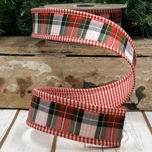 May include: A spool of decorative ribbon with a red and white plaid pattern and a red and white striped edge. The ribbon is made of fabric and is suitable for crafts and gift wrapping.