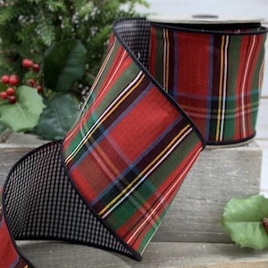 Pode incluir: Uma fita de tecido larga com um padrão xadrez vermelho, verde e amarelo de um lado e um padrão de xadrez vichy preto e branco no verso. As bordas da fita são finalizadas com uma costura preta ao longo de todo o comprimento.