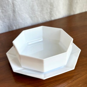 May include: A white octagonal bowl and matching plate. The bowl is sitting on top of the plate.