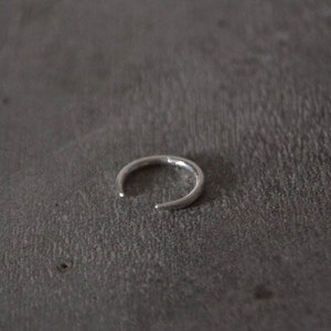 以下が含まれることがあります： シンプルなオープンサークルデザインのシルバーリング。リングは金属製で、滑らかで磨かれた仕上げになっています。