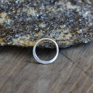 May include: A silver ring with a hammered texture. The ring is round and has a smooth, polished finish.