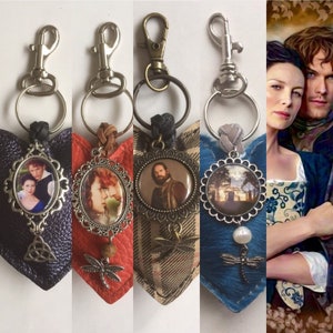 Może przedstawiać: Cztery breloki w kształcie serca z różnymi wzorami tkanin i zawieszkami. Każdy brelok ma okrągłą metalową zawieszkę z innym obrazkiem w środku. Zawieszki przedstawiają parę, kobietę, mężczyznę i krajobraz. Breloki są przymocowane do srebrnych kółek do kluczy.