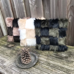 Può includere: Tre cuscini decorativi con un motivo a scacchi. I cuscini sono in pelliccia sintetica nera, bianca, beige e marrone.