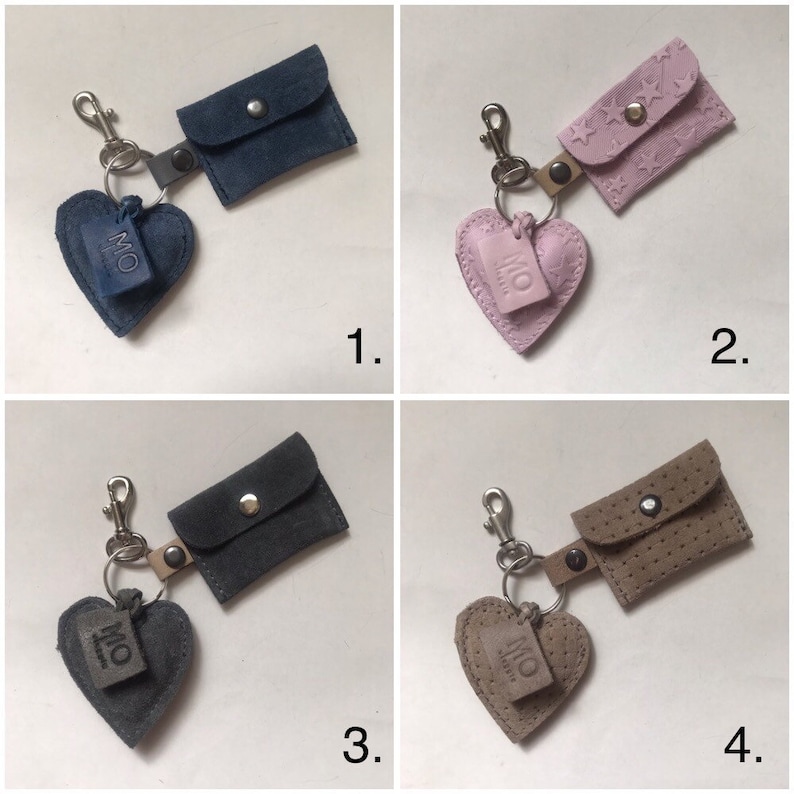 May include: Four keychains featuring a heart-shaped charm embossed with the letters MO and a small rectangular pouch with a snap closure. The set includes a dark blue, a light pink with star patterns, a dark gray, and a beige perforated pouch.